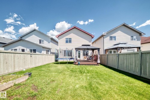 Expansive fenced backyard featuring a grassy lawn, a wooden deck, and a covered gazebo - 3224 26 Street, Edmonton, AB 