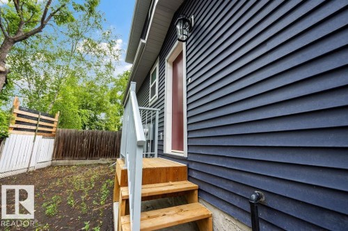 Dark blue horizontal siding with white trim around a red exterior door - 6204 150 Avenue, Edmonton, AB 