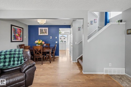 Open-concept main level featuring wood-finish flooring, a distinct accent wall, and a staircase with white railings - 2123 36 Avenue, Edmonton, AB - Indoor