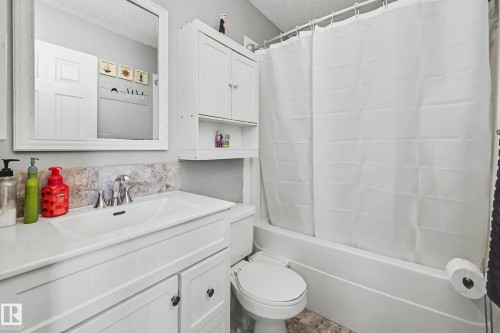 Bathroom featuring a white vanity with integrated sink, chrome faucet, and decorative tile backsplash - 2123 36 Avenue, Edmonton, AB - Indoor Photo Showing Bathroom