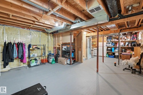 Unfinished basement featuring exposed wood joists, structural support beams, and light grey painted concrete flooring - 2123 36 Avenue, Edmonton, AB - Indoor Photo Showing Basement