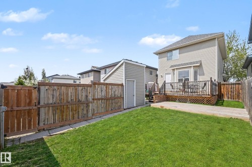 Expansive backyard featuring a manicured lawn, a concrete patio area, and a private wood deck with lattice skirting - 2123 36 Avenue, Edmonton, AB - Outdoor With Deck Patio Veranda With Exterior