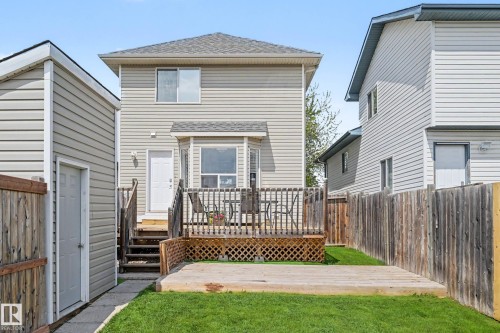 Rear exterior featuring a raised wooden deck, ground-level wooden patio, and a manicured lawn - 2123 36 Avenue, Edmonton, AB - Outdoor With Deck Patio Veranda With Exterior