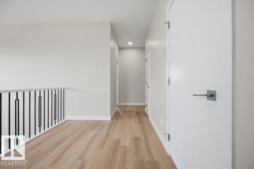 Hallway featuring wood-finish flooring, white walls, and recessed lighting - 15004 62 Street, Edmonton, AB 