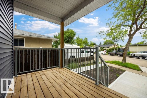 Covered porch featuring wood decking, metal railings, and a wood support post - 15004 62 Street, Edmonton, AB 