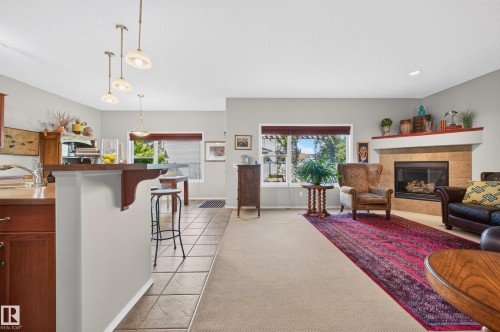 Living area featuring a stone-surround fireplace with a wood mantel, a large picture window, and recessed lighting - 1310 82 Street, Edmonton, AB 