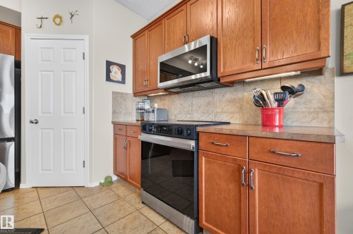 Kitchen featuring wood cabinetry, stainless steel microwave, and a dark countertop - 1310 82 Street, Edmonton, AB 