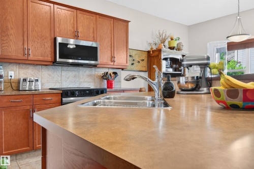 Kitchen featuring wood-finish cabinetry, stainless steel appliances, and a double basin sink - 1310 82 Street, Edmonton, AB 