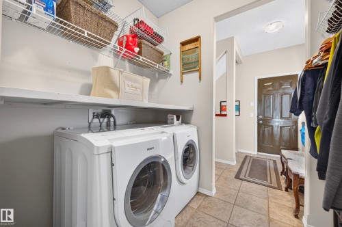 Dedicated laundry area featuring a front-loading washer and dryer, practical shelving, and wire racks for organized storage - 1310 82 Street, Edmonton, AB 