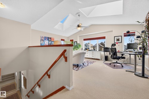Loft space featuring vaulted ceilings, a ceiling fan, two skylights, and multiple windows - 1310 82 Street, Edmonton, AB 
