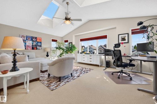 Vaulted ceiling with skylight and ceiling fan, featuring multiple windows with red blinds, and light-toned carpeting throughout - 1310 82 Street, Edmonton, AB 