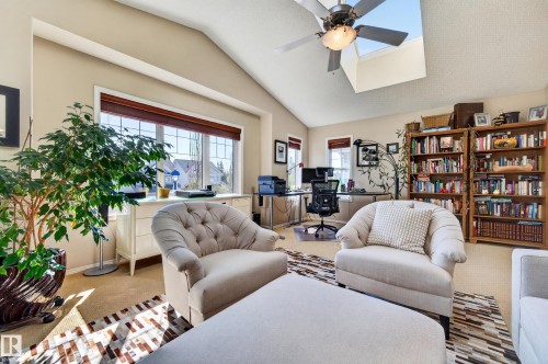 Vaulted ceiling with an integrated skylight and ceiling fan, large picture window with wood blinds, built-in shelving, carpet flooring, and a recessed wall niche - 1310 82 Street, Edmonton, AB 