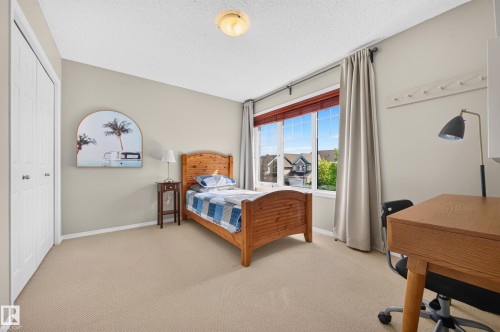 Bright room featuring a large window with white trim and wooden blinds, beige wall color, and textured beige carpeting - 1310 82 Street, Edmonton, AB 