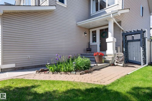 Front entrance featuring a covered porch with a substantial white column, light brown siding, and a paver walkway - 1310 82 Street, Edmonton, AB 