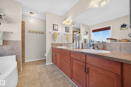 Bathroom featuring a double vanity with wood cabinetry and countertop, two undermount sinks, and a full-width wall mirror - 1310 82 Street, Edmonton, AB 