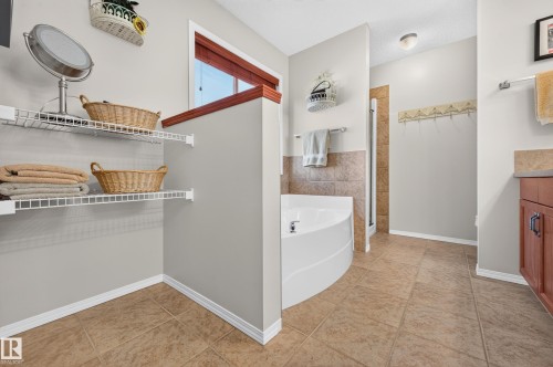 Contemporary bathroom featuring an integrated corner tub, a tiled shower enclosure, and a vanity with a stone-finish countertop - 1310 82 Street, Edmonton, AB 