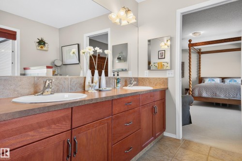 Double vanity featuring wood cabinetry, integrated sinks, a tiled backsplash, and a large wall-mounted mirror - 1310 82 Street, Edmonton, AB 