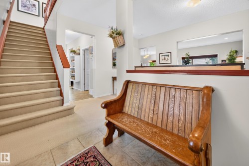 Inviting entryway with a carpeted staircase featuring a wood handrail - 1310 82 Street, Edmonton, AB 