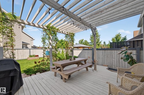 Expansive outdoor deck featuring a light-toned pergola with trailing greenery and string lighting - 1310 82 Street, Edmonton, AB 