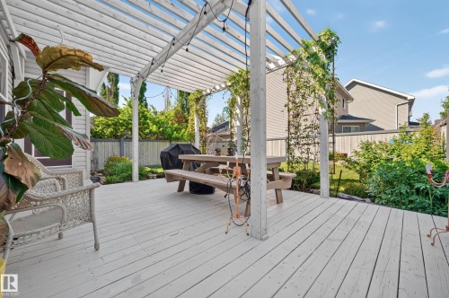 Spacious outdoor deck featuring a white pergola, wood-finish flooring, and mature perimeter landscaping - 1310 82 Street, Edmonton, AB 