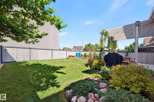 Landscaped backyard featuring a paver patio and a slatted wood pergola - 1310 82 Street, Edmonton, AB 