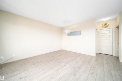 Spacious room featuring wood-finish flooring, neutral wall tones, a modern ceiling light fixture, and a five-panel interior door - 