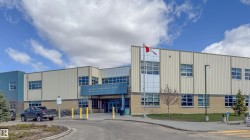 Modern institutional building with a two-story elevation, showcasing horizontal metal panel siding and a brick base - 
