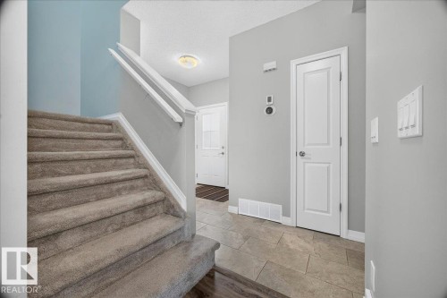 Carpeted staircase with white trim, complemented by light gray walls and durable tile flooring - 17203 71 Street, Edmonton, AB 
