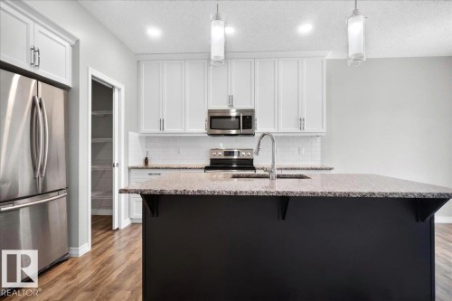 Modern kitchen featuring a dark island with an undermount sink and gooseneck faucet - 17203 71 Street, Edmonton, AB 