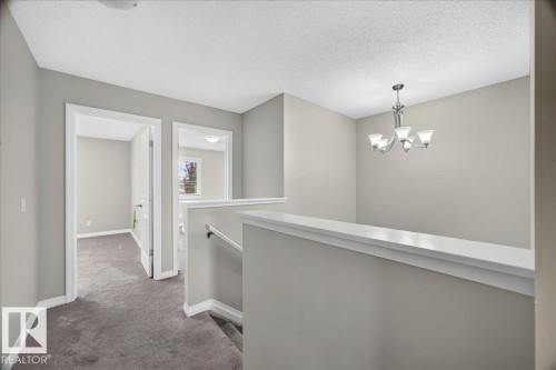 Upper-level hallway featuring a chandelier, light gray wall paint, and gray carpeting - 17203 71 Street, Edmonton, AB 