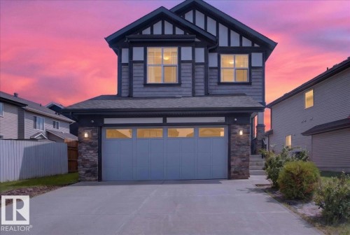 Two-story residence featuring a two-car garage with a paneled door, stone accents on the facade, and a concrete driveway - 17203 71 Street, Edmonton, AB 