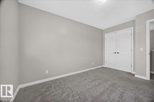 Neutral tone wall paint with white trim, gray carpet flooring, and double bifold doors - 17203 71 Street, Edmonton, AB 
