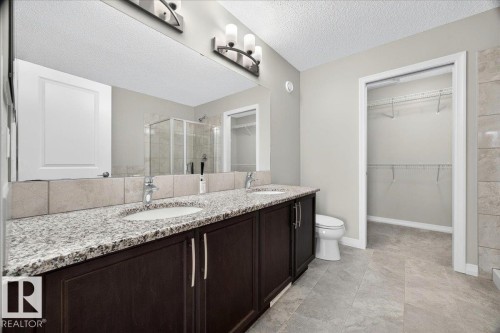 Bathroom featuring a dual vanity with granite countertops, dark wood-finish cabinetry, and undermount sinks - 17203 71 Street, Edmonton, AB 