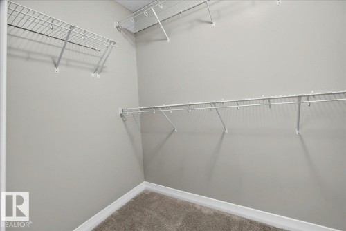 Walk-in closet with carpet flooring, light gray wall paint, white trim, and white wire shelving - 17203 71 Street, Edmonton, AB 