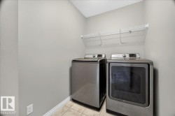 Dedicated laundry area featuring a tile floor and light gray walls - 
