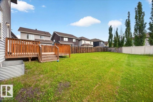 Expansive backyard with a large wood deck featuring a railing and steps - 17203 71 Street, Edmonton, AB 