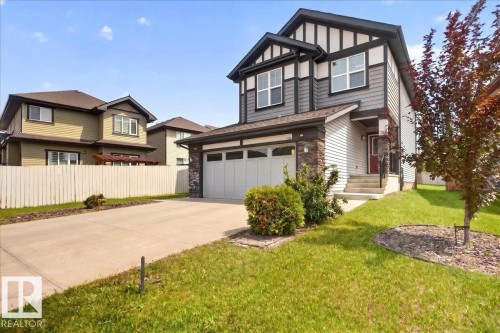 Two-story residence featuring a two-car garage, concrete driveway, and a red front door - 17203 71 Street, Edmonton, AB 