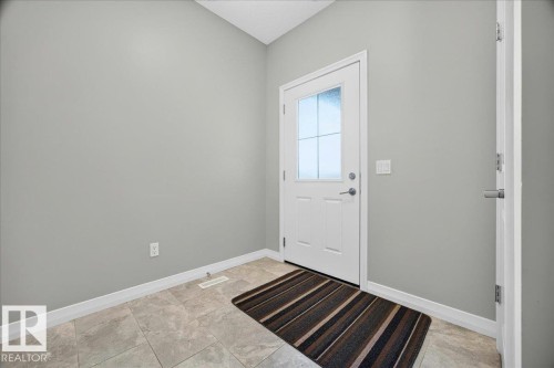 Entryway featuring a white paneled door with decorative glass inserts, light grey walls, and light-toned tile flooring - 17203 71 Street, Edmonton, AB 