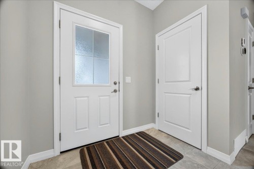 Foyer featuring a white entry door with frosted glass panes and a white paneled interior door, complemented by light gray wall paint and tile flooring - 17203 71 Street, Edmonton, AB 