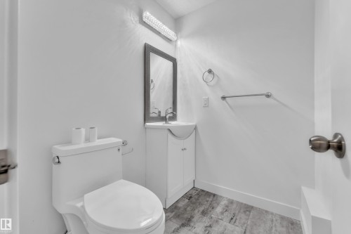 Bathroom featuring a contemporary vanity with an integrated sink, framed mirror, and wood-finish flooring - 144 Sunwapta Way, Edmonton, AB 