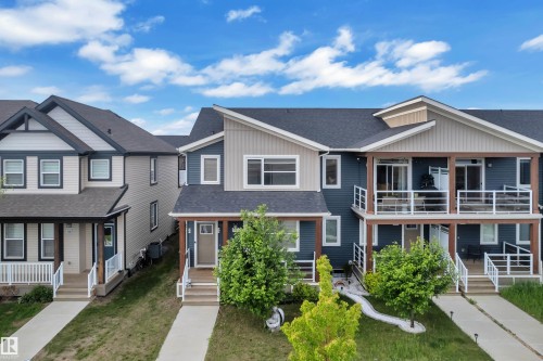 Contemporary townhome exterior featuring multi-level balconies with white railings, dark blue and light siding, and an asphalt shingle roof - 144 Sunwapta Way, Edmonton, AB 