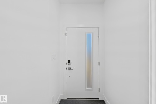 Modern entry door featuring a frosted glass insert and smart lock system - 415 42 Street, Edmonton, AB 