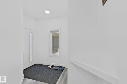 Entryway featuring contemporary light wood-finish flooring, a white paneled door with a vertical glass insert, and a recessed ceiling light - 415 42 Street, Edmonton, AB 