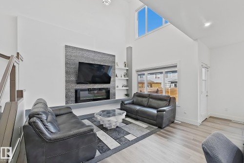 Spacious living area featuring a vaulted ceiling and an accent wall with an integrated electric fireplace - 415 42 Street, Edmonton, AB 