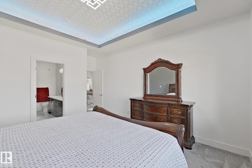 Spacious bedroom featuring light-toned carpet flooring and a tray ceiling with integrated lighting - 415 42 Street, Edmonton, AB 