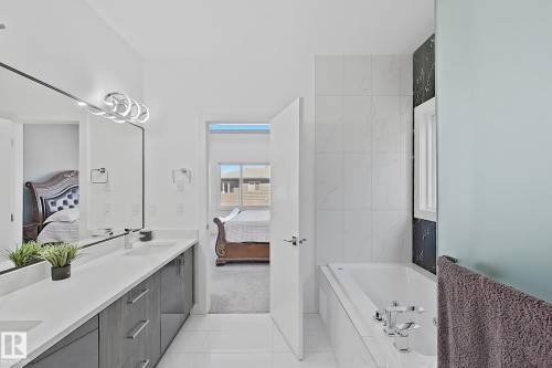 Contemporary bathroom featuring a long double vanity with stone countertops and undermount sinks - 415 42 Street, Edmonton, AB 