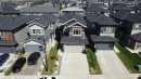 Modern two-story residence featuring a gray and brown siding exterior, a two-car garage with frosted glass panel accents, and a concrete driveway - 415 42 Street, Edmonton, AB 