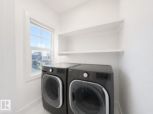 Bright utility room featuring a large window with white trim, built-in shelving, and white baseboards - 415 42 Street, Edmonton, AB 