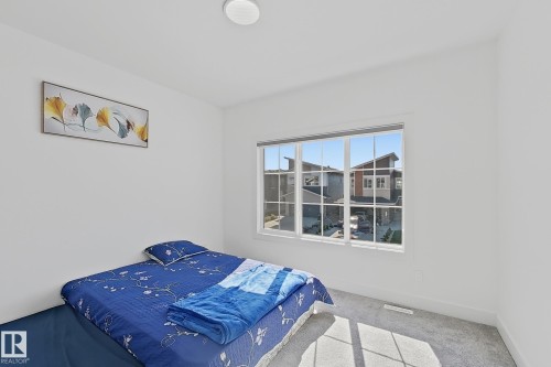Bright room featuring a large multi-pane window, white walls, and light gray carpet flooring - 415 42 Street, Edmonton, AB 