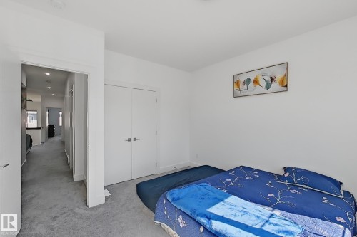 Bedroom featuring a neutral gray carpet, white walls, and a white bi-fold closet door - 415 42 Street, Edmonton, AB 